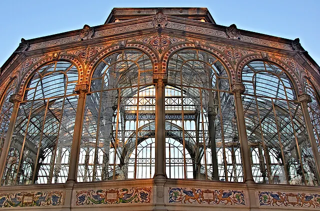 A close view of the iron and glass arches of the Crystal Palace in the Retiro park, with its decorated tiled base