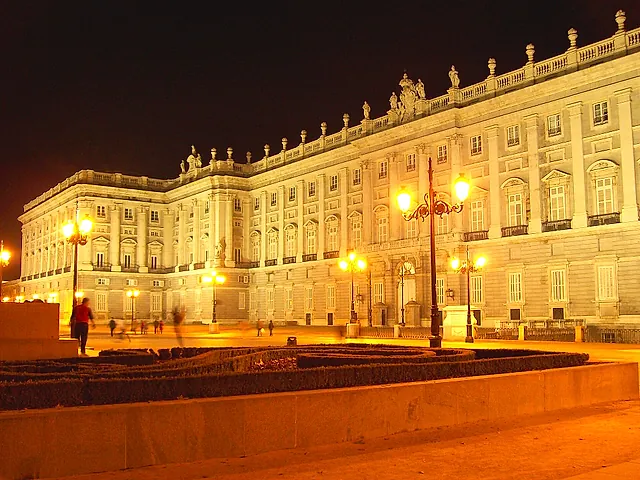 The Royal Palace of Madrid lit up at night, with golden light on its long façade
