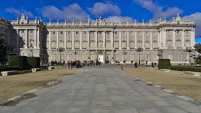 The Royal Palace of Madrid seen from the Plaza de Oriente, with its long pale façade under a blue sky