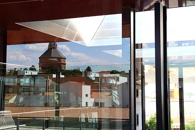 Madrid rooftops and a dome seen through the glass walls of the Nouvel building of the Reina Sofía Museum